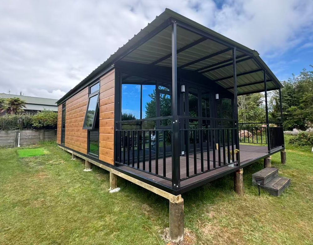 Flat roof double-wing expandable container house with curved veranda on a lawn