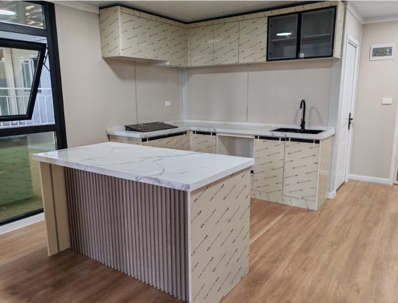 Kitchen with island bench and marble-look benchtop inside a HuoSheng expandable home